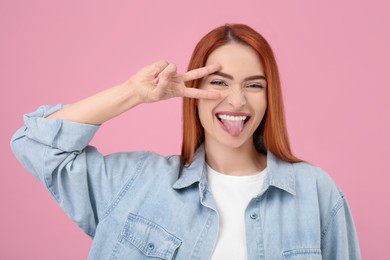 Happy woman showing her tongue on pink background