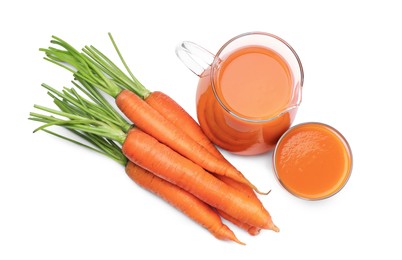 Glass and pitcher of freshly made carrot juice on white background, top view