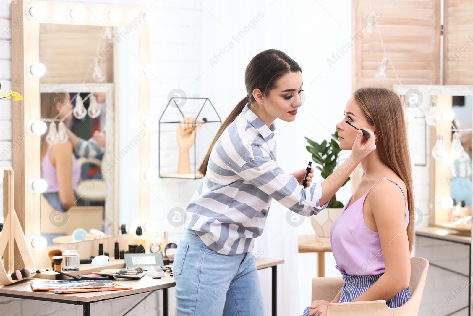 Photo of Professional visage artist applying makeup on woman's face in salon