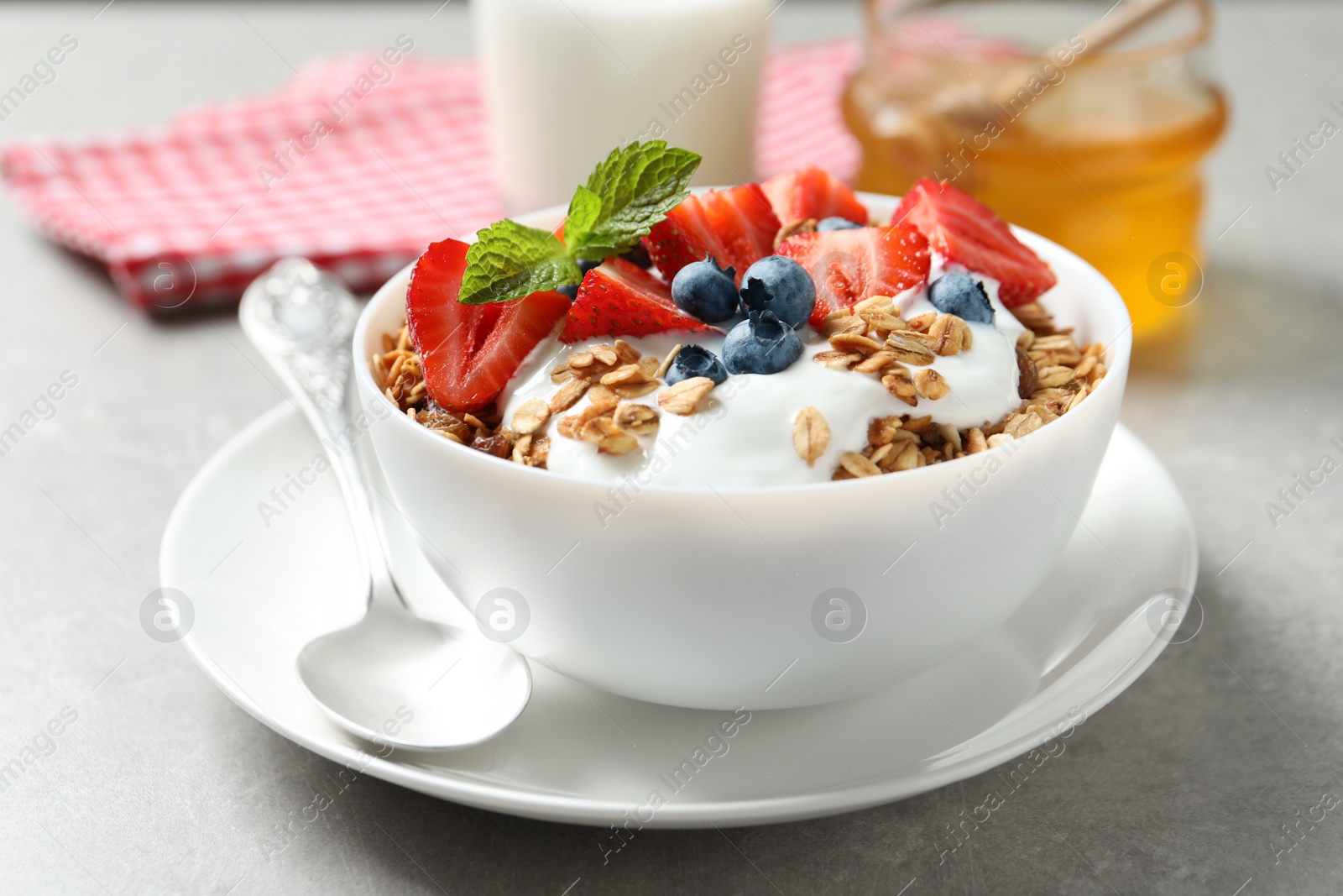 Image of Tasty granola with yogurt and berries served for breakfast on light table