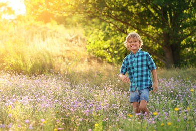 Photo of Cute little boy outdoors, space for text. Child spending time in nature