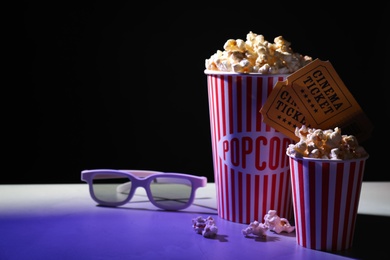 Photo of Delicious popcorn, glasses and tickets on table