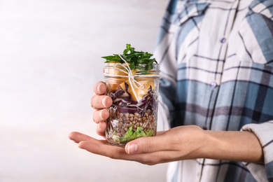 Photo of Woman holding glass jar with healthy meal, closeup