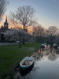 Photo of Canal with moored boats outdoors. Sky reflecting in water