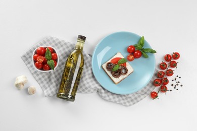 Delicious sandwich with cream cheese, anchovies and tomatoes on white table, flat lay