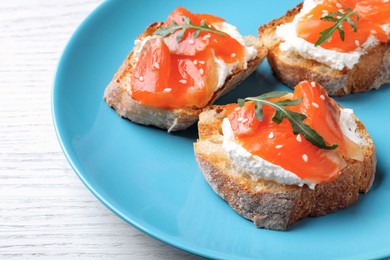 Photo of Delicious sandwiches with cream cheese, salmon and arugula on white wooden table, closeup