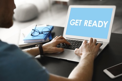 Image of Man using laptop with phrase Get Ready at table, closeup