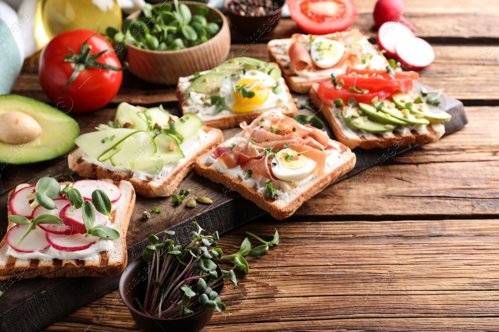 Photo of Different delicious sandwiches with microgreens on wooden table