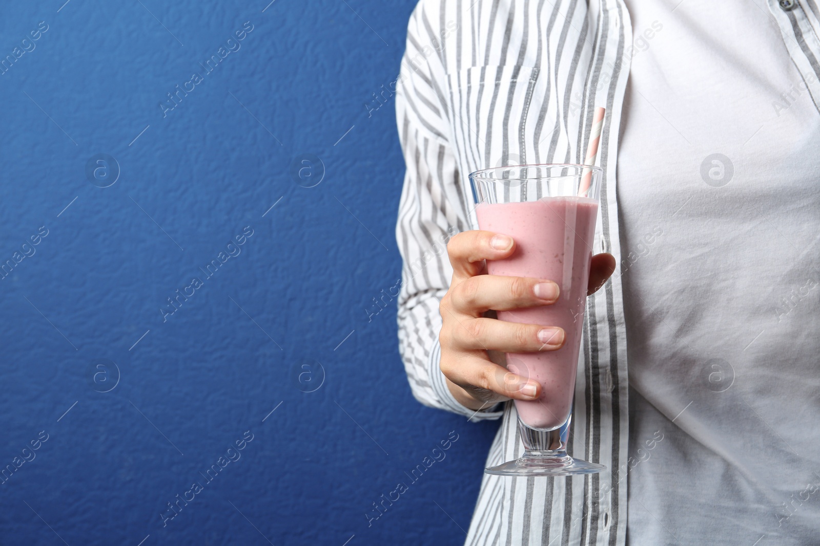 Image of Woman with glass of tasty smoothie on blue background, closeup. Space for text 