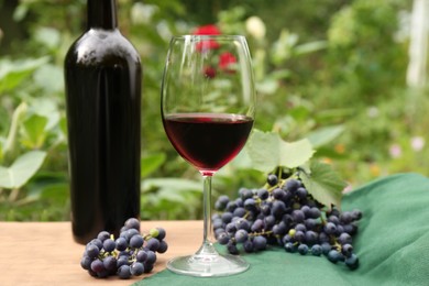 Red wine and grapes on wooden table outdoors