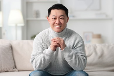 Portrait of smiling man on sofa indoors