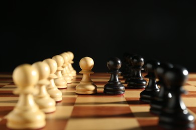Photo of Black and white pawns on chessboard against dark background, closeup. Competition concept