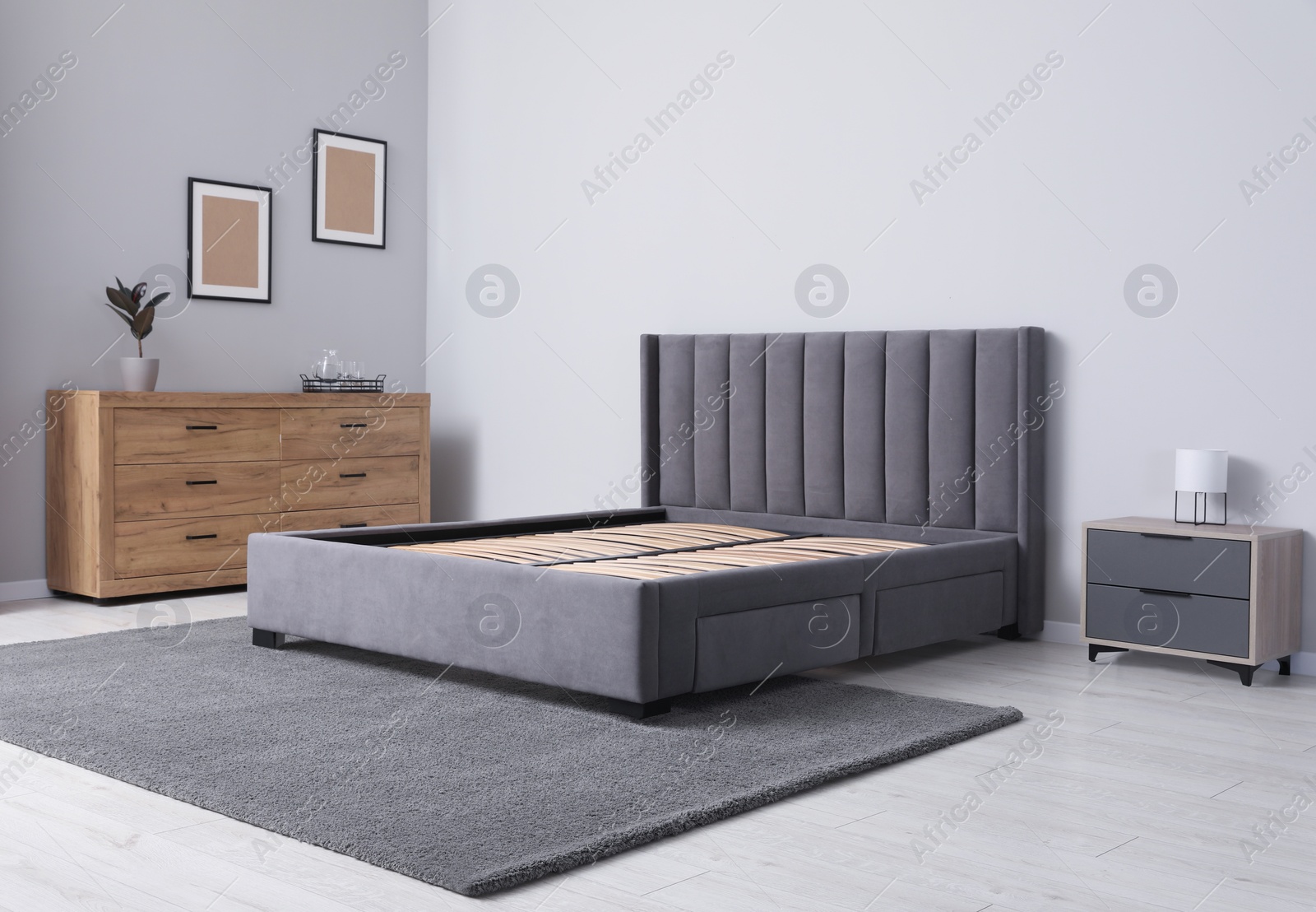 Photo of Comfortable bed with storage space for bedding under slatted base in stylish room