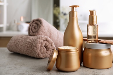 Different hair care products, towels and comb on table in bathroom