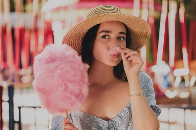 Beautiful young woman with cotton candy having fun at funfair