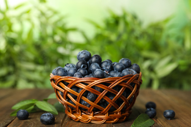 Tasty ripe blueberries in wicker bowl on wooden table