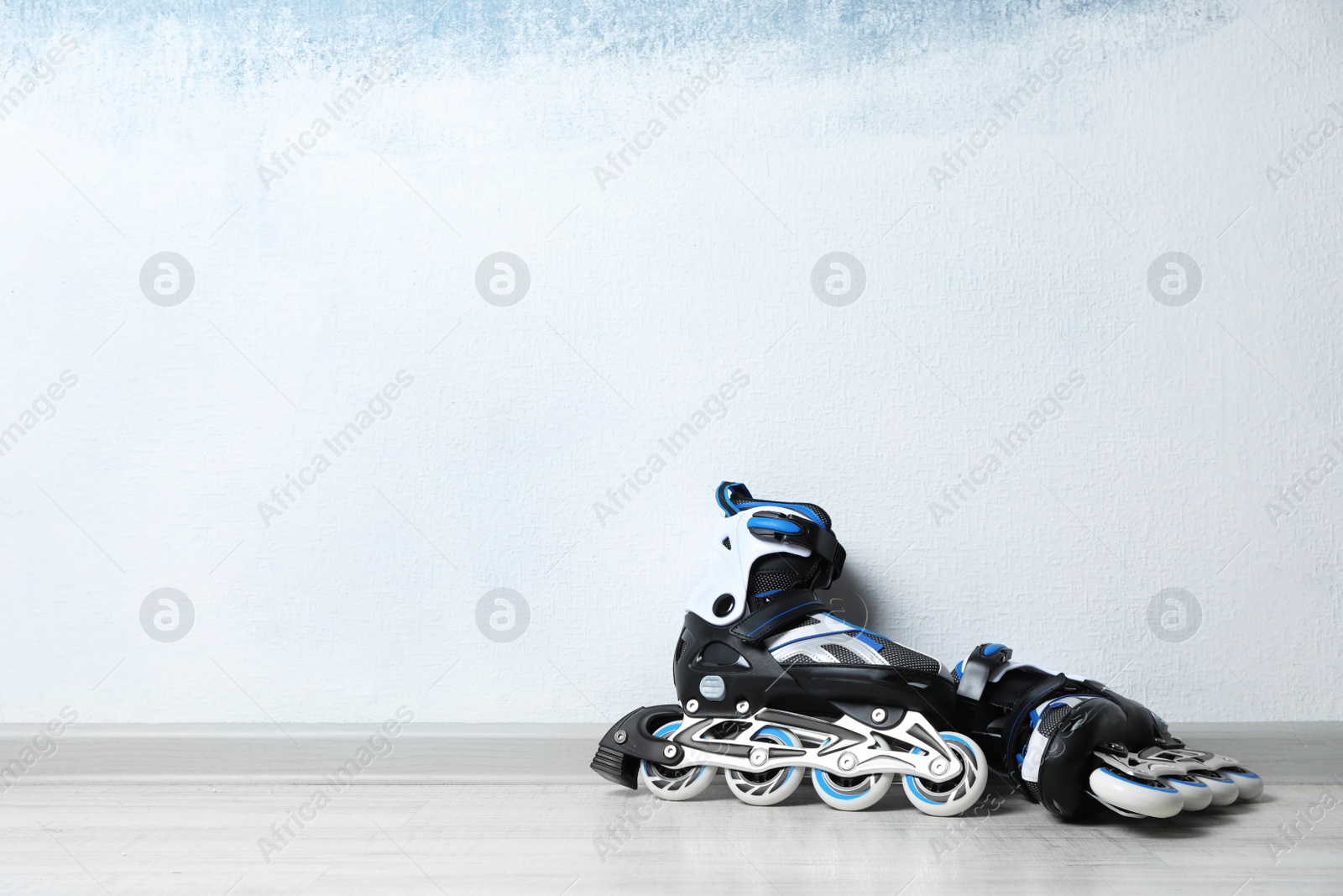 Photo of Inline roller skates on floor near color wall. Space for text