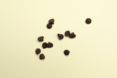 Delicious chocolate chips on beige background, top view