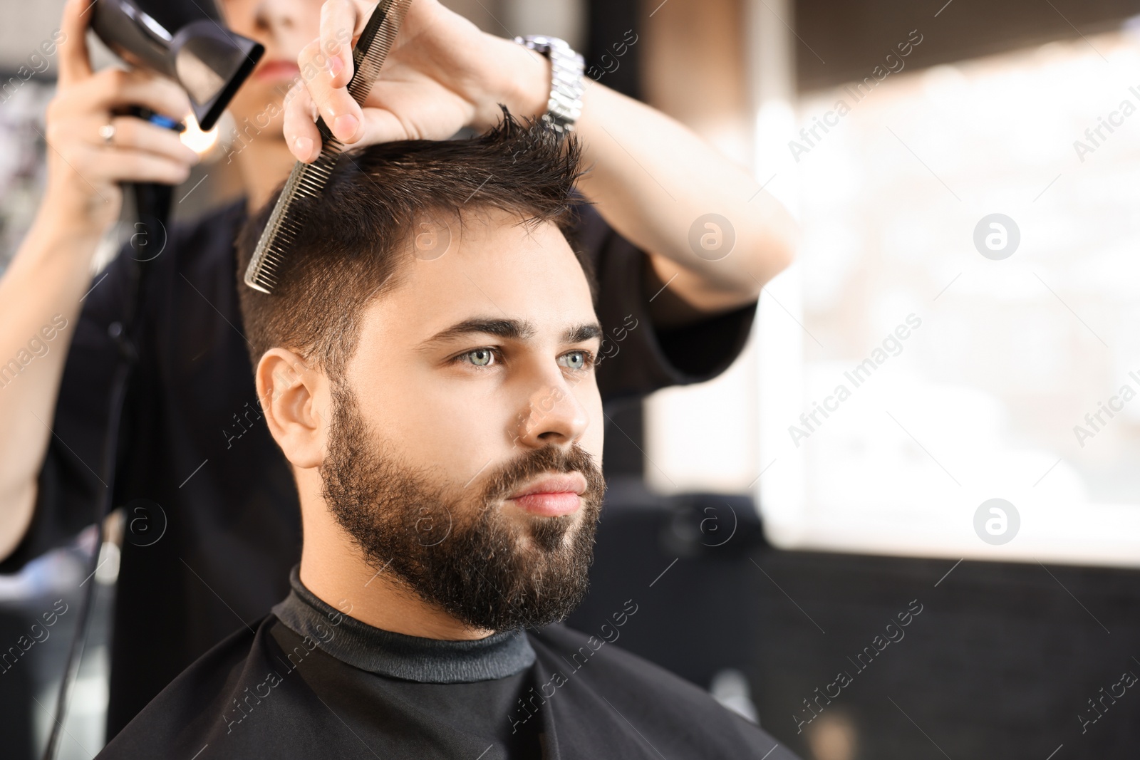 Photo of Professional hairdresser working with client in barbershop