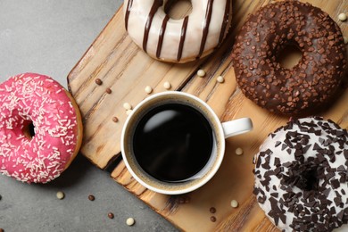 Yummy donuts with sprinkles and coffee on grey table, flat lay