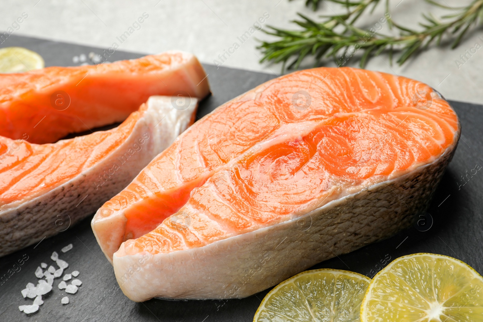 Photo of Fresh salmon and ingredients for marinade on black board, closeup