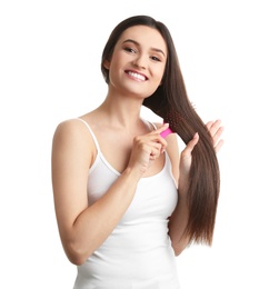 Beautiful young woman with hair brush on white background