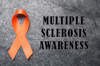  Multiple Sclerosis Awareness Day. Orange ribbon on grey background, top view