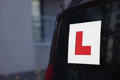 L-plate on car outdoors, closeup with space for text. Driving school