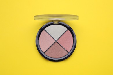 Photo of Colorful contouring palette on yellow background, top view. Professional cosmetic product