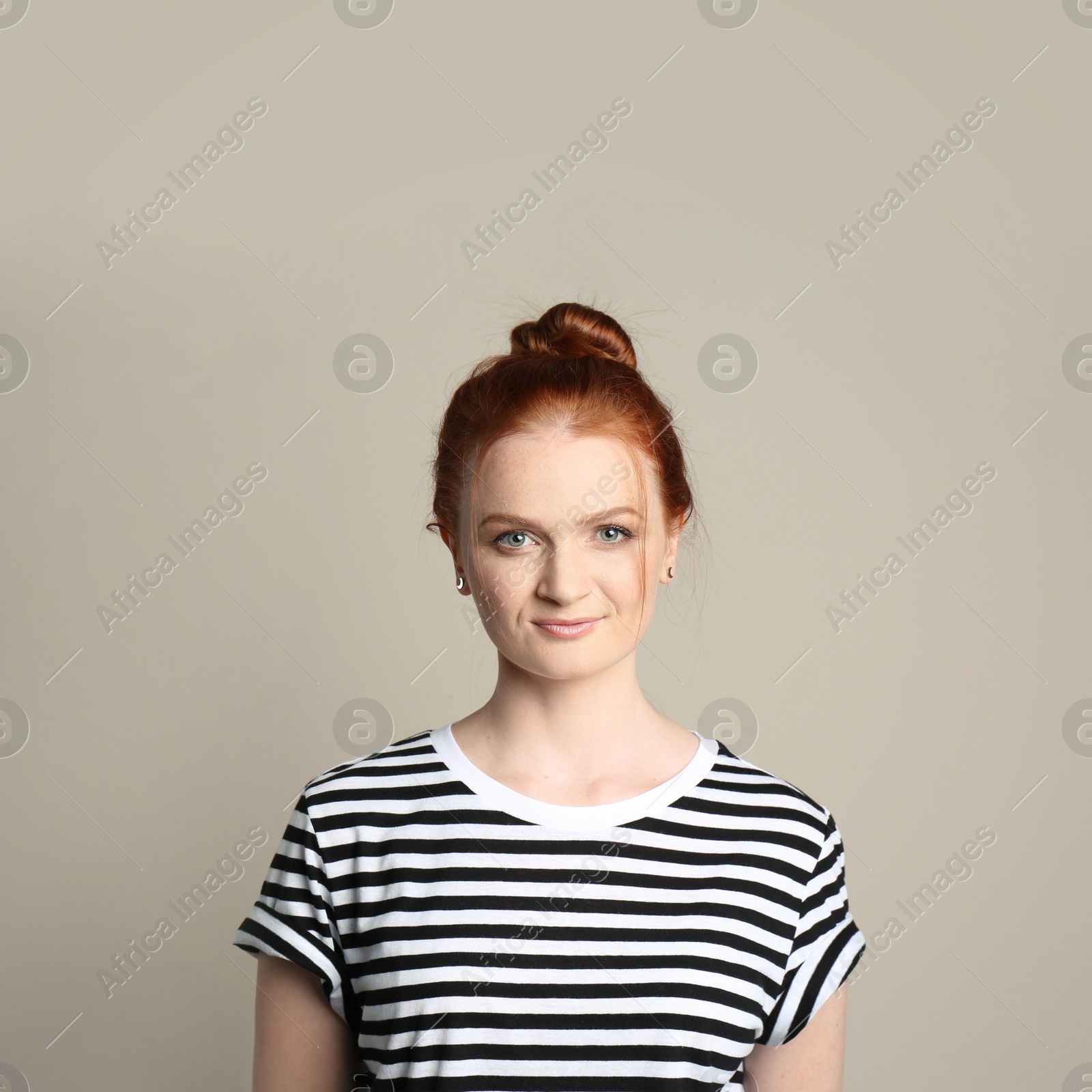 Photo of Candid portrait of happy red haired woman with charming smile on beige background