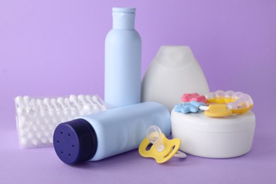 Photo of Different skin care products for baby, cotton buds, rattle and pacifier on violet background