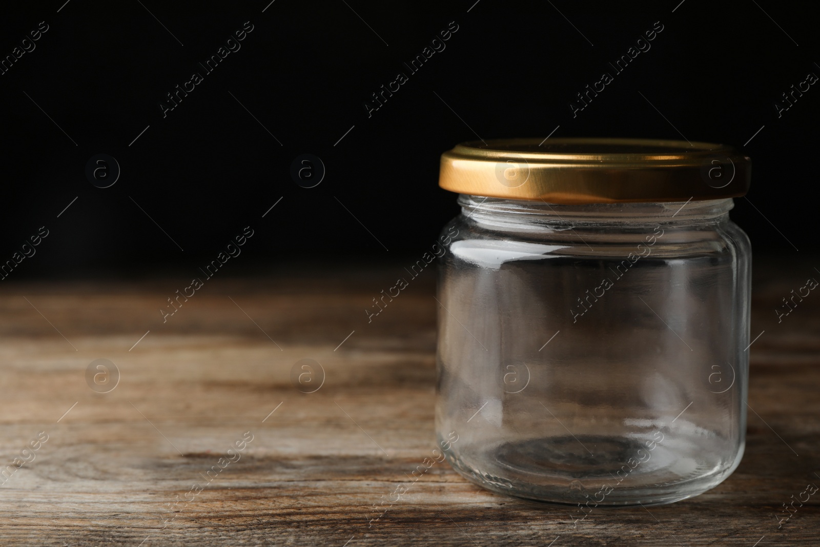 Photo of Empty glass jar on wooden table, space for text