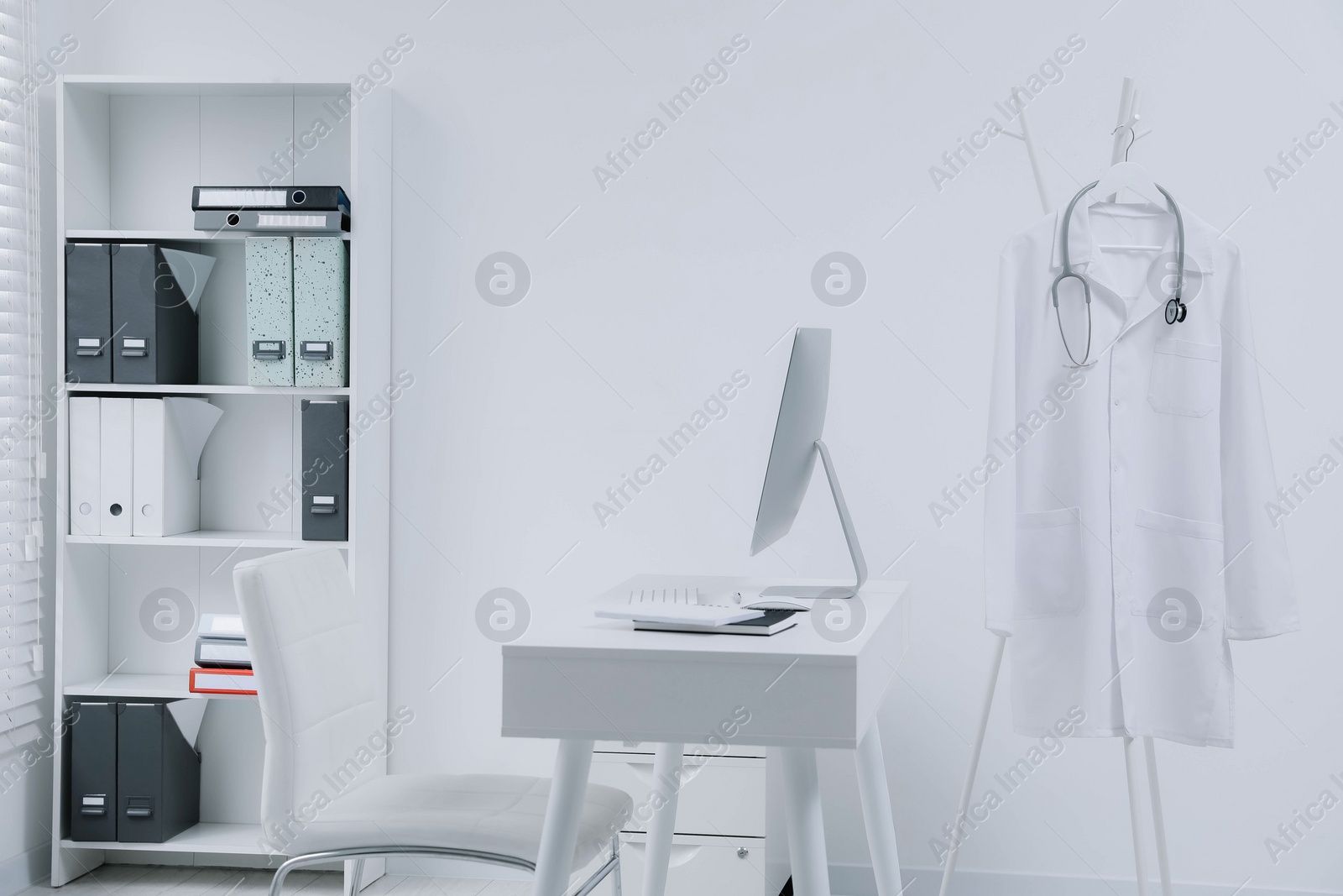 Photo of White doctor's gown and stethoscope hanging on rack in clinic