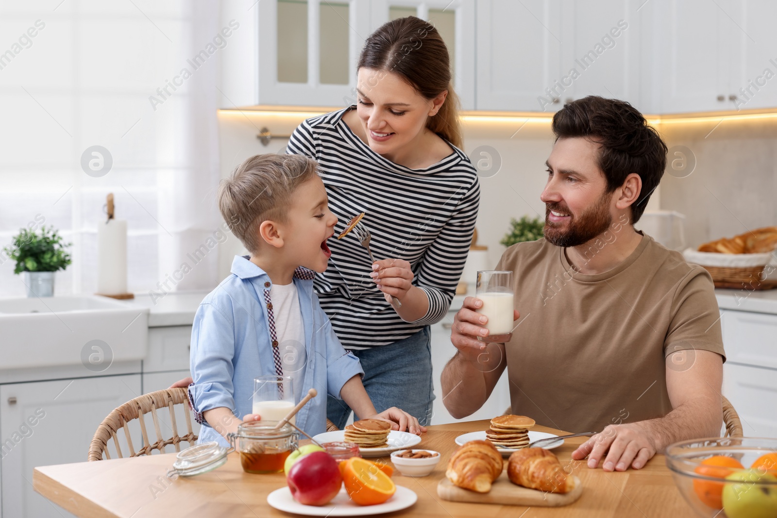 Photo of Happy family having breakfast at table in kitchen