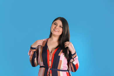 Beautiful overweight woman posing on light blue background. Plus size model