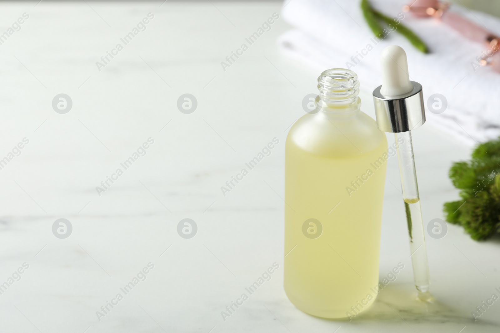 Photo of Bottle of hydrophilic oil and pipette on white table, space for text