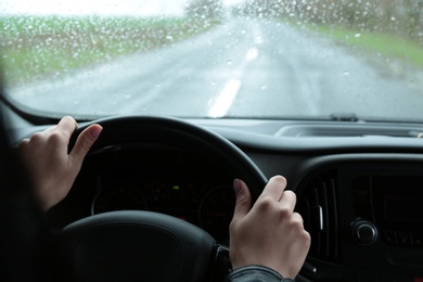 Woman driving car on rainy day, closeup of hands