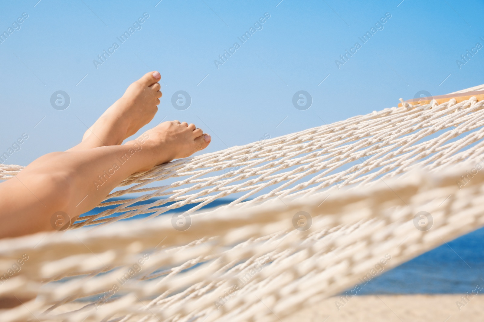 Photo of Young woman relaxing in hammock on beach, closeup