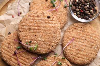 Tasty vegan cutlets with breadcrumbs and spices on wooden board, top view