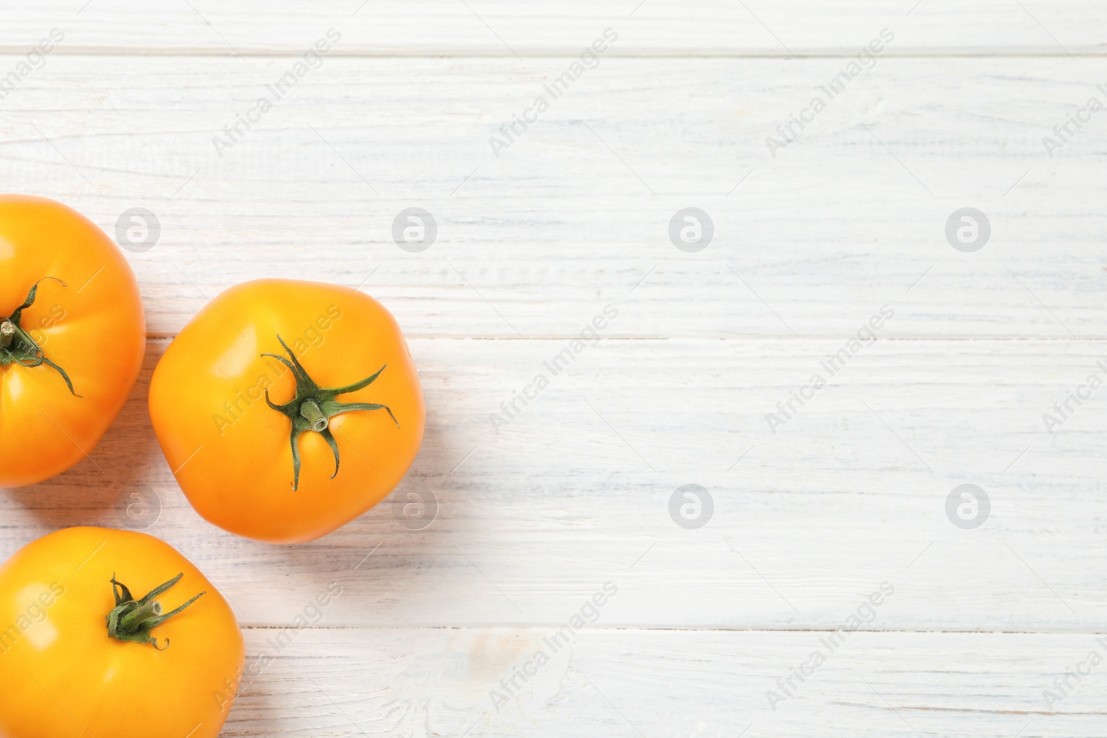 Photo of Fresh ripe yellow tomatoes on white wooden table, flat lay. Space for text