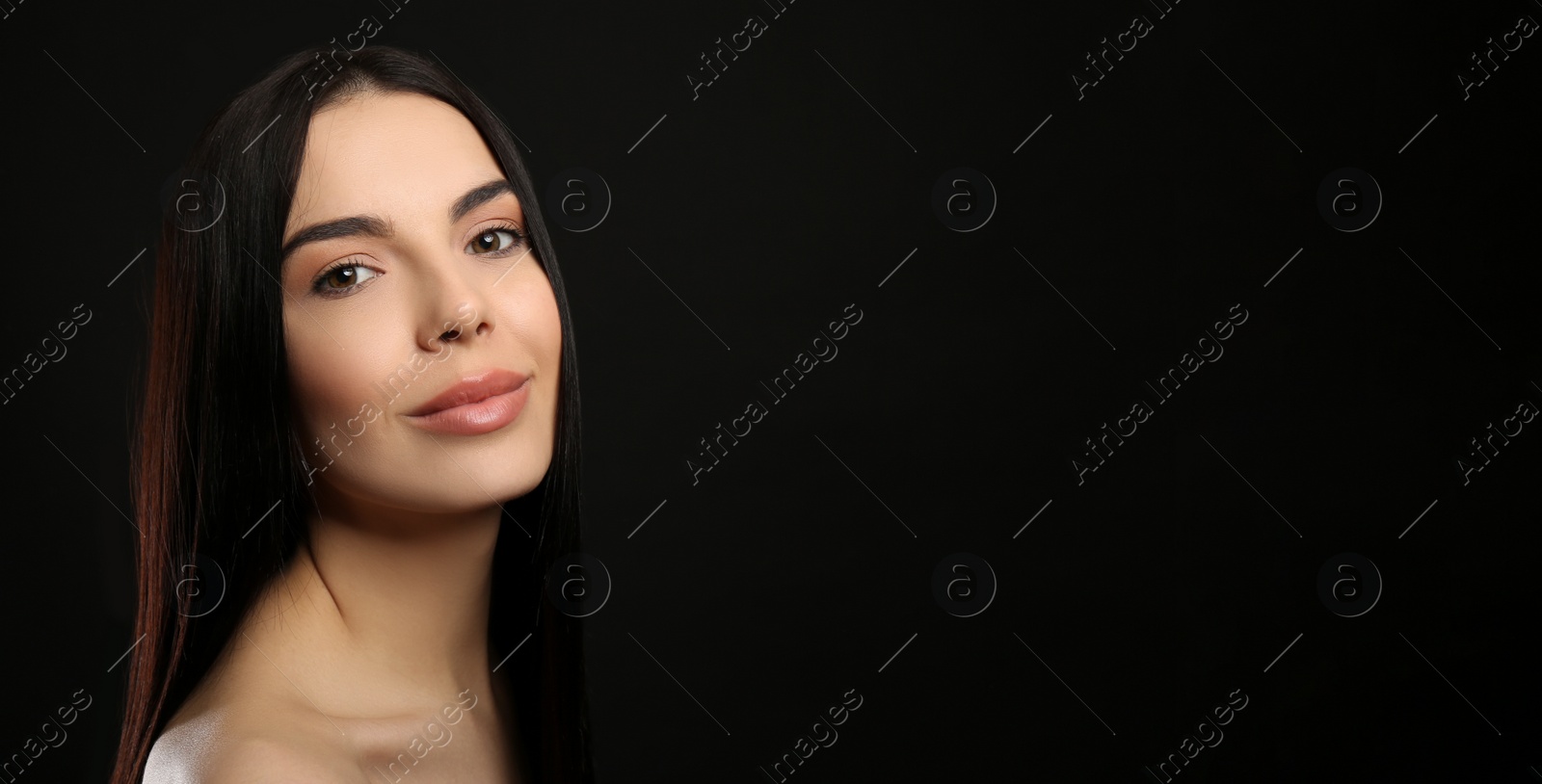 Photo of Portrait of happy young woman with beautiful black hair and charming smile on dark background, space for text