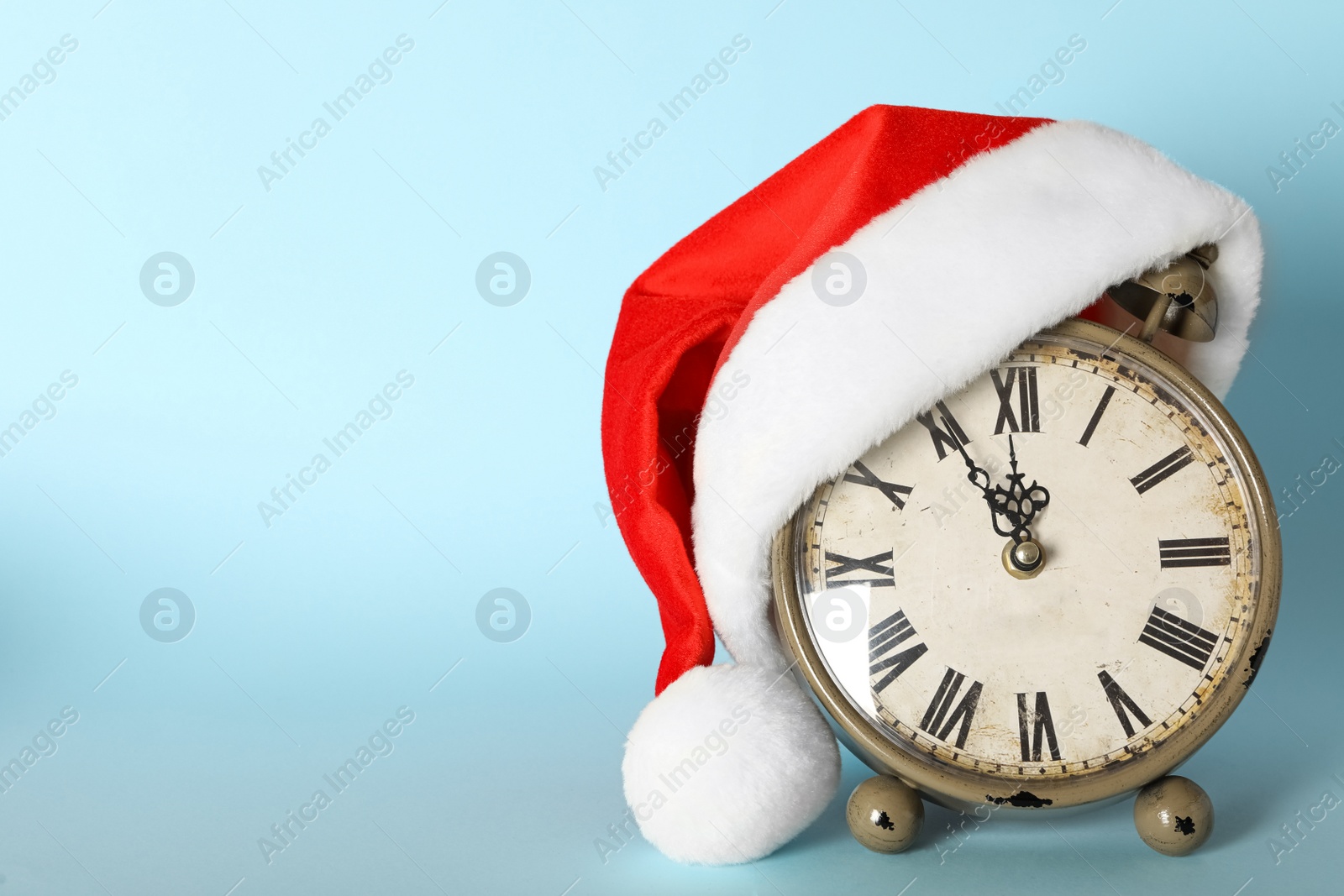 Photo of Vintage alarm clock with Christmas decor on light blue background, space for text. New Year countdown