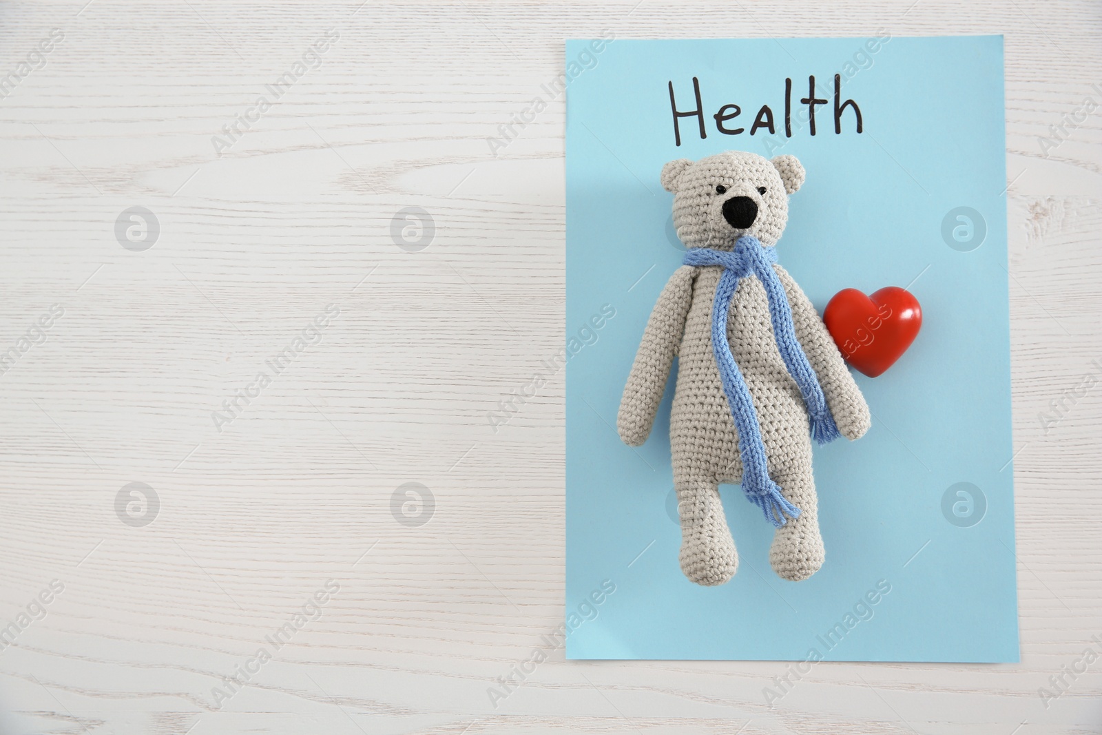 Photo of Toy bear, heart, sheet of paper with word HEALTH and space for text on wooden background, top view. Children's doctor