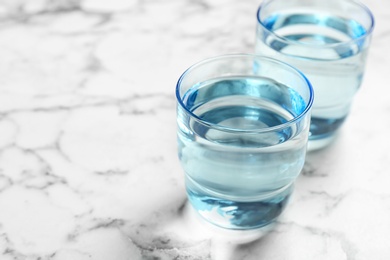 Photo of Glasses with fresh water on marble table. Space for text