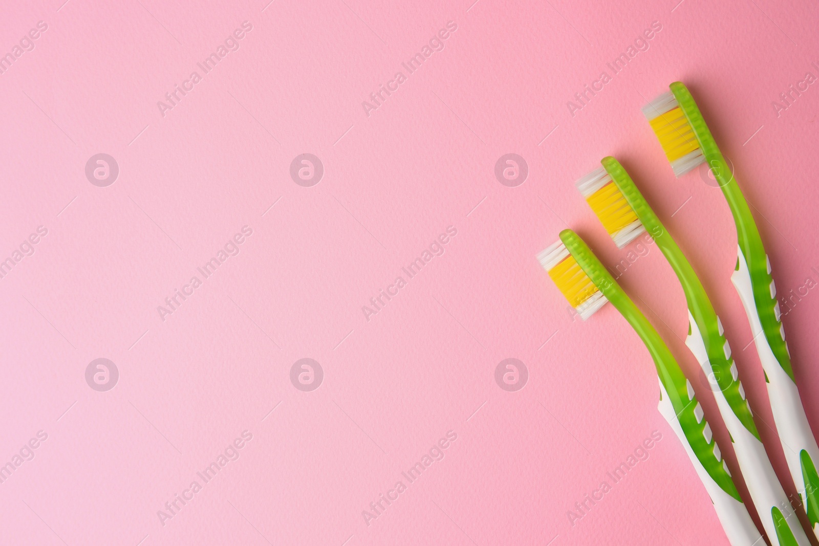 Photo of Toothbrushes on pink background, flat lay. Space for text