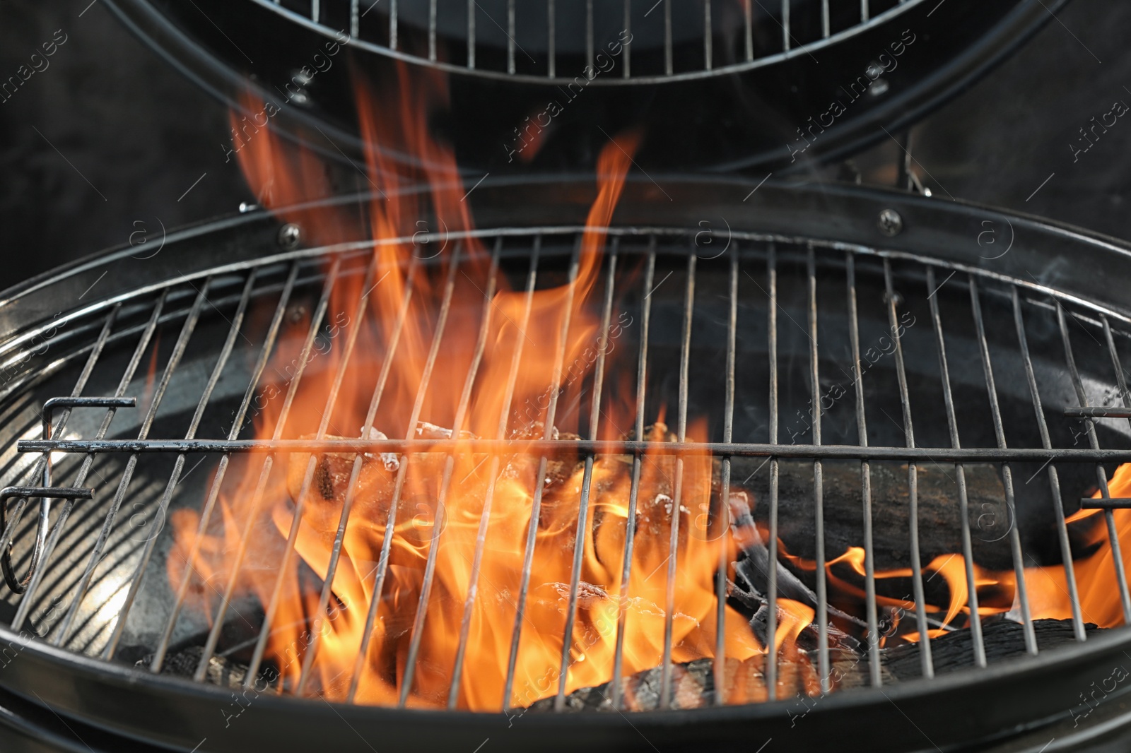 Photo of New modern barbecue grill with burning firewood, closeup