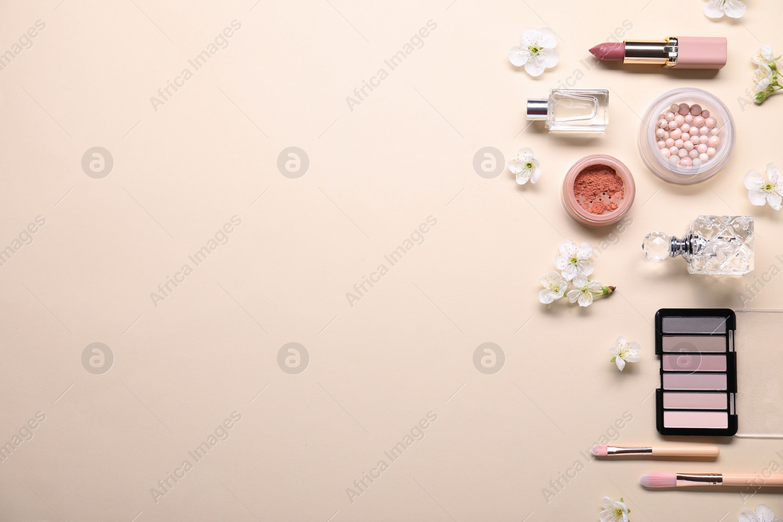 Photo of Flat lay composition with different makeup products and beautiful spring flowers on beige background, space for text