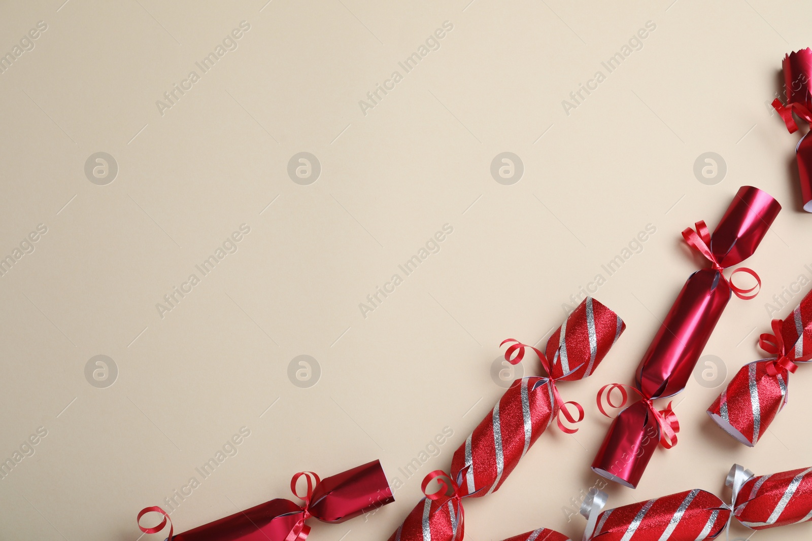 Photo of Red Christmas crackers on beige background, flat lay. Space for text