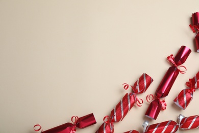 Red Christmas crackers on beige background, flat lay. Space for text