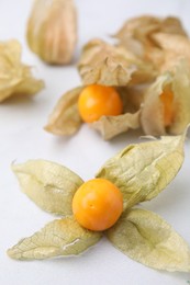 Ripe physalis fruits with calyxes on white marble table, closeup